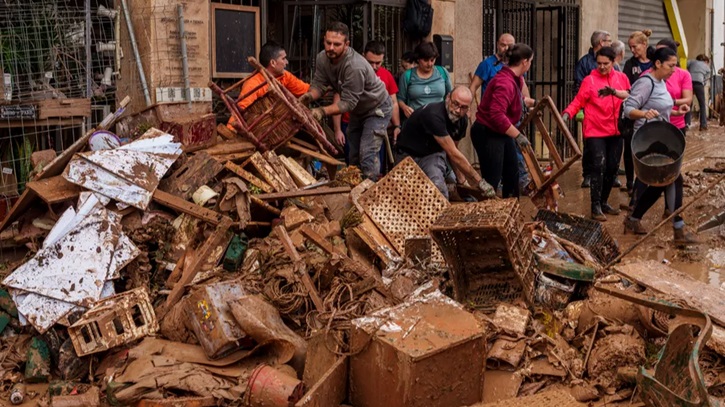 Mud-caked volunteers clean flood debris in a Spanish town as authorities struggle to respond